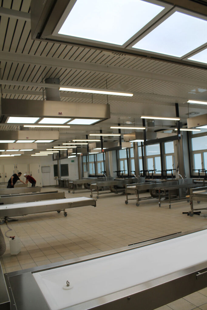 Dissection room with extracted dissection table and height-adjustable OP-course station (world novelty - in each case in front left). Barrier-free for imaging via C-bow. Plastic body tray.